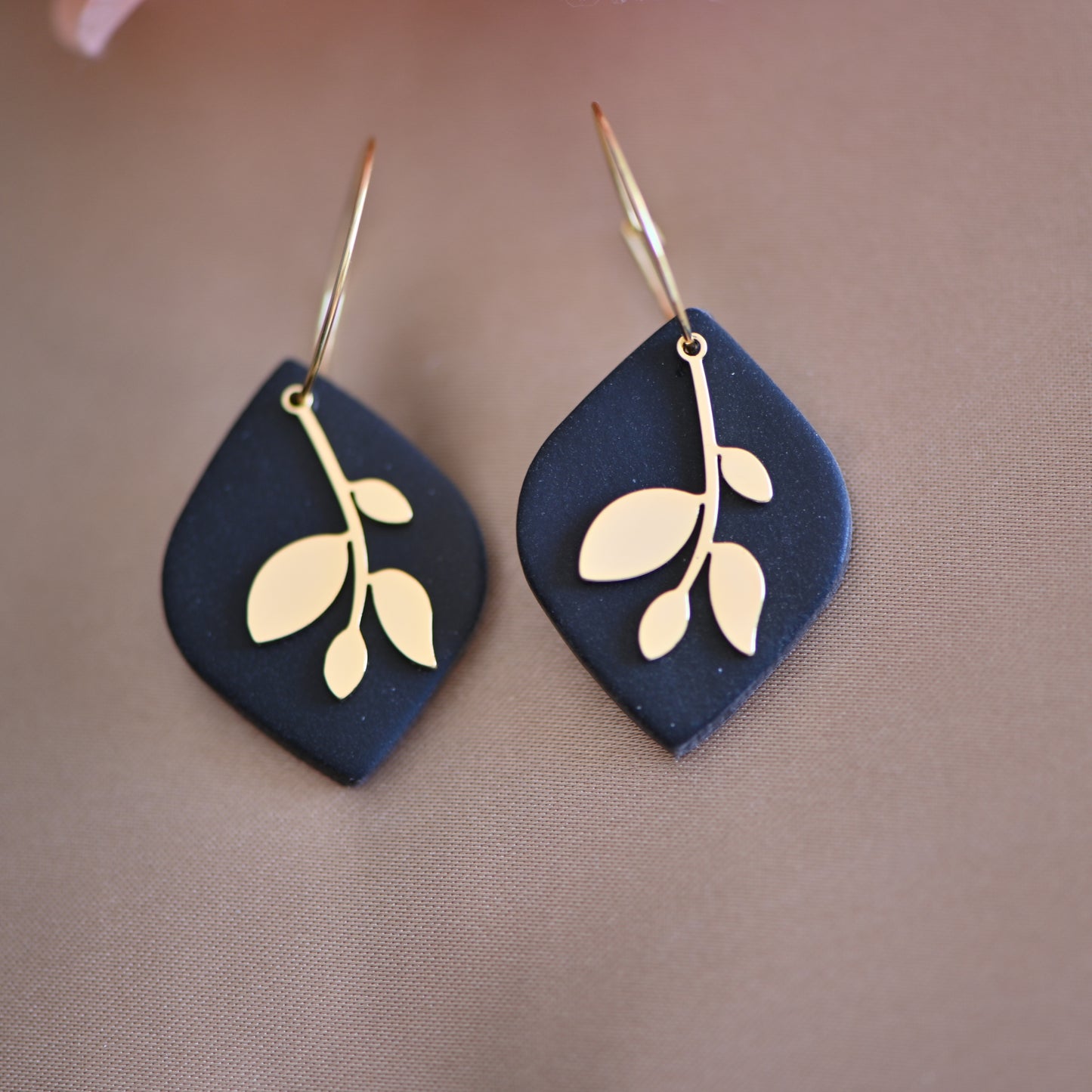 Black earrings , with gold hoops and gold leave charm