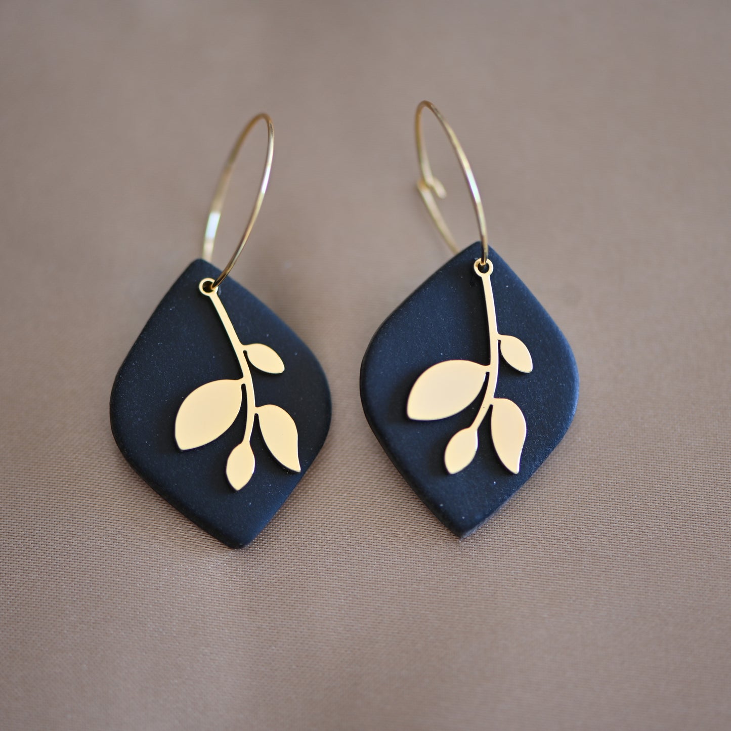 Black earrings , with gold hoops and gold leave charm