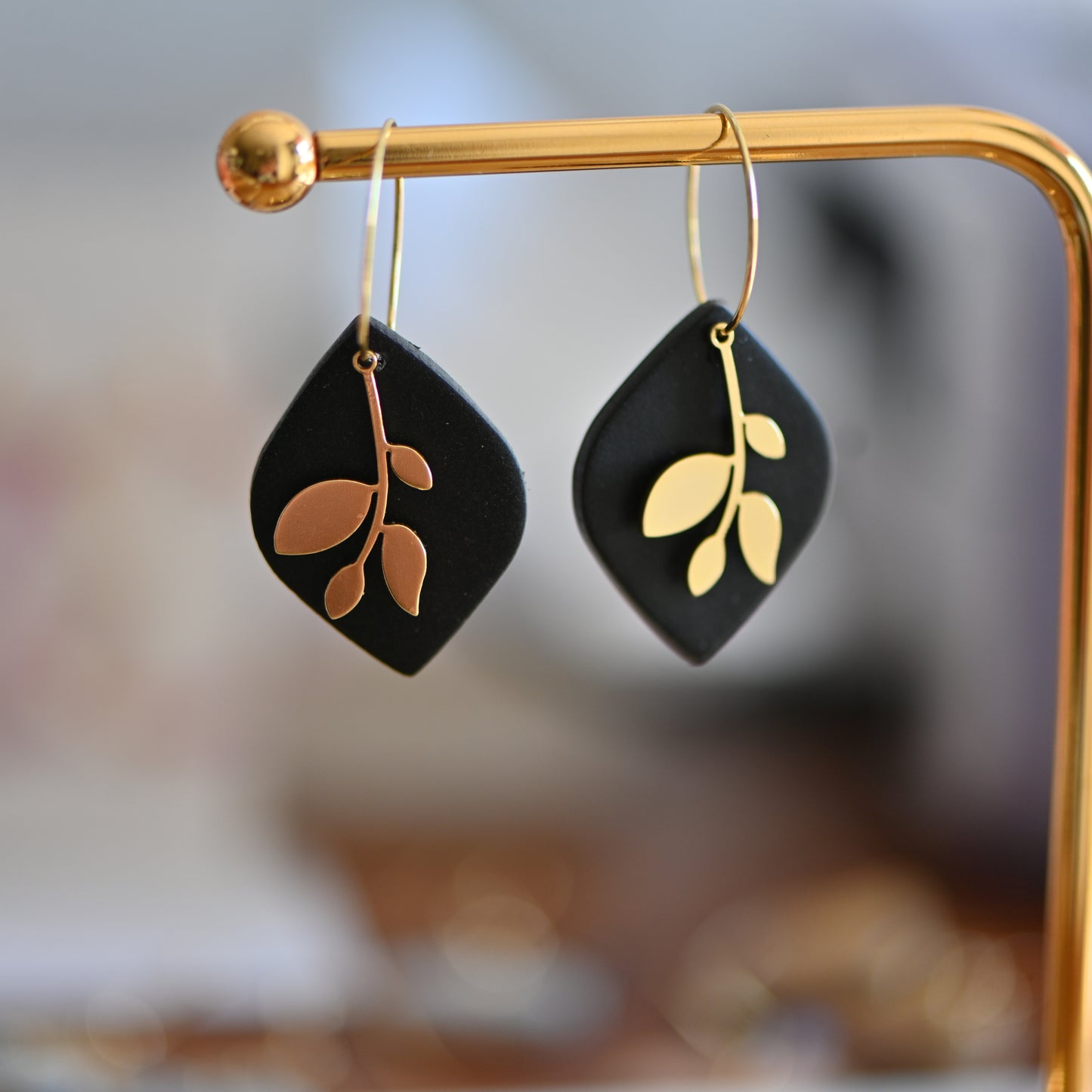 Black earrings , with gold hoops and gold leave charm