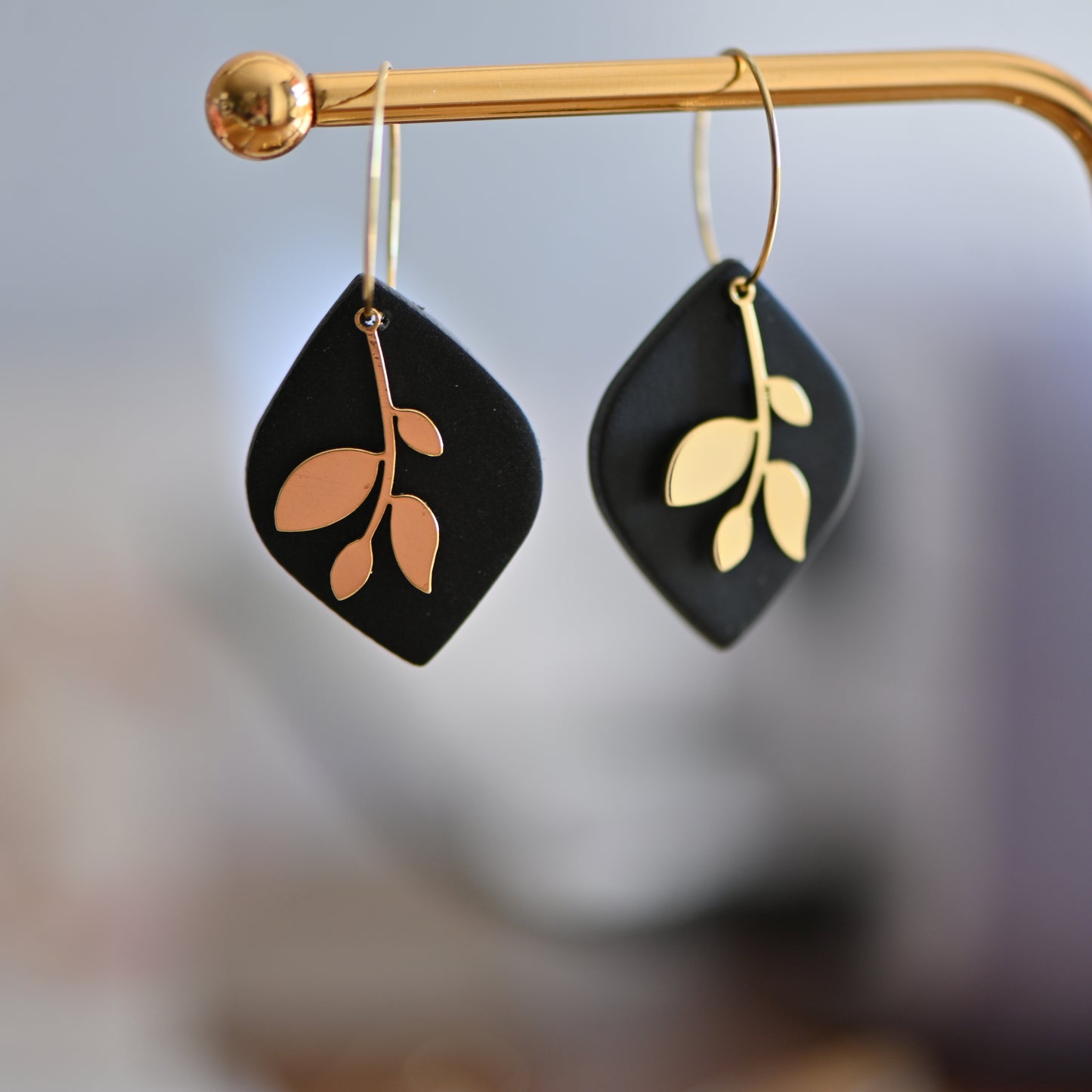 Black earrings , with gold hoops and gold leave charm